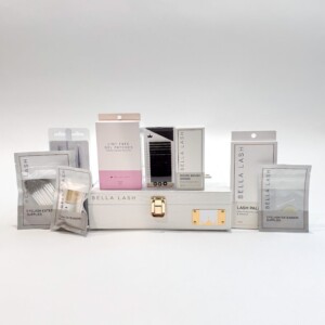 A white Bella Lash kit box surrounded by various eyelash extension supplies and products in labeled packaging.